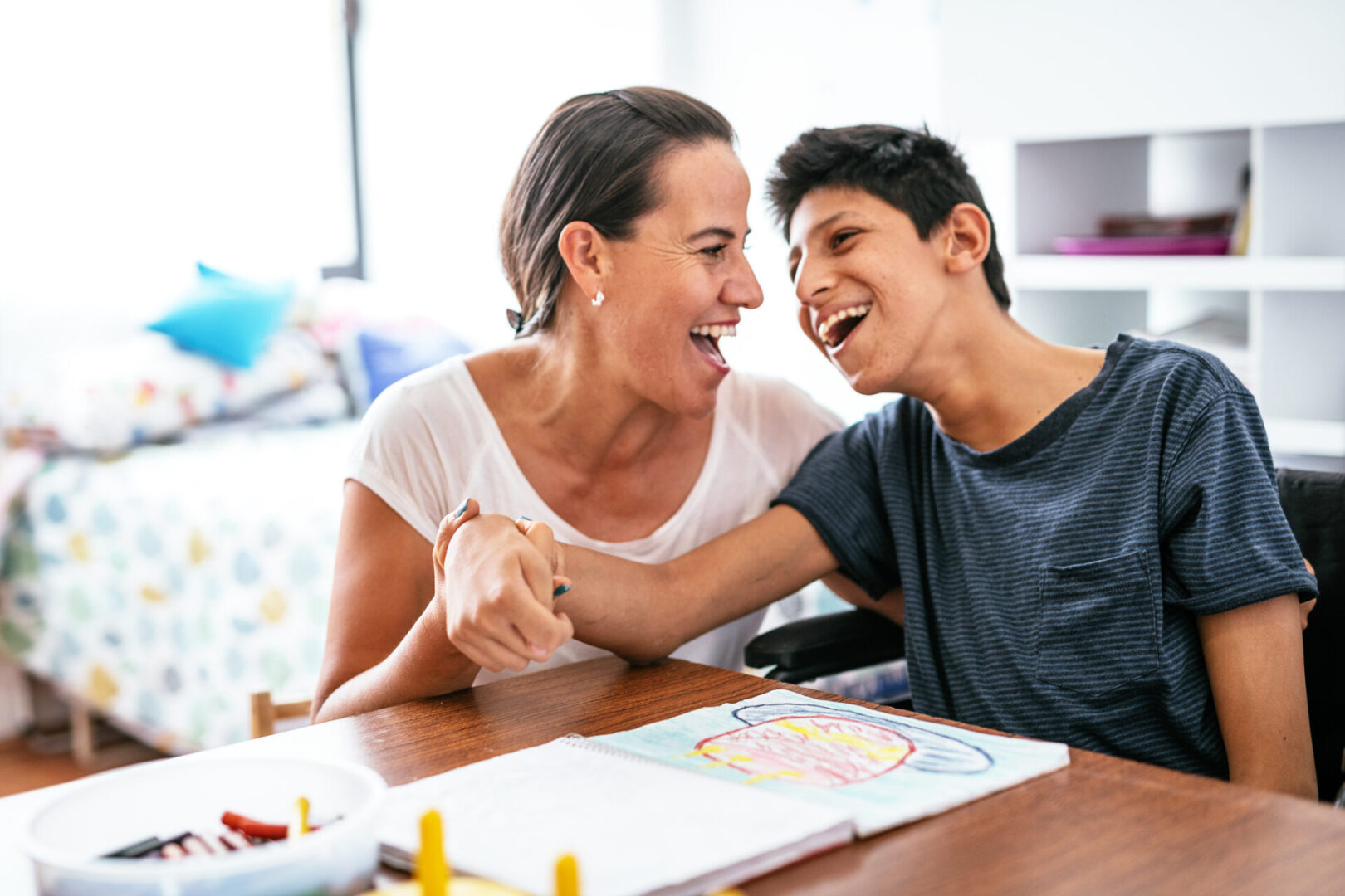 A woman and boy sitting at table with coloring book.