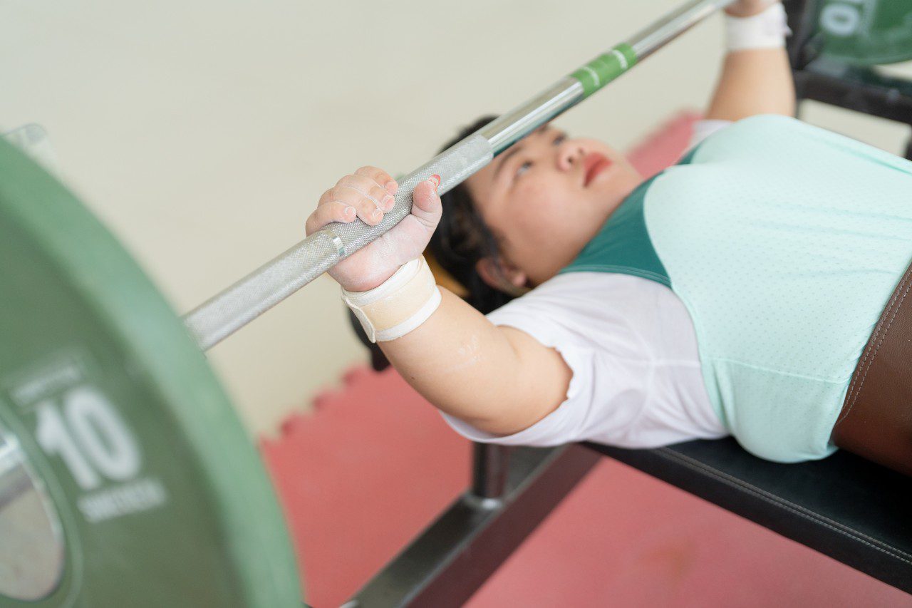 A woman is lifting a barbell in the gym.